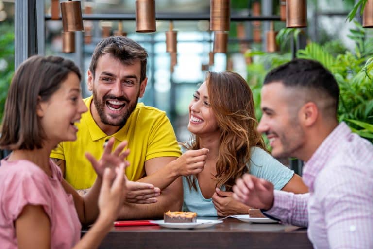 Cheerful friends having dessert and talking in cafe