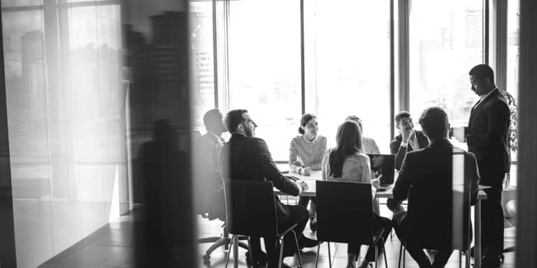 guy standing at head of business table 2X1